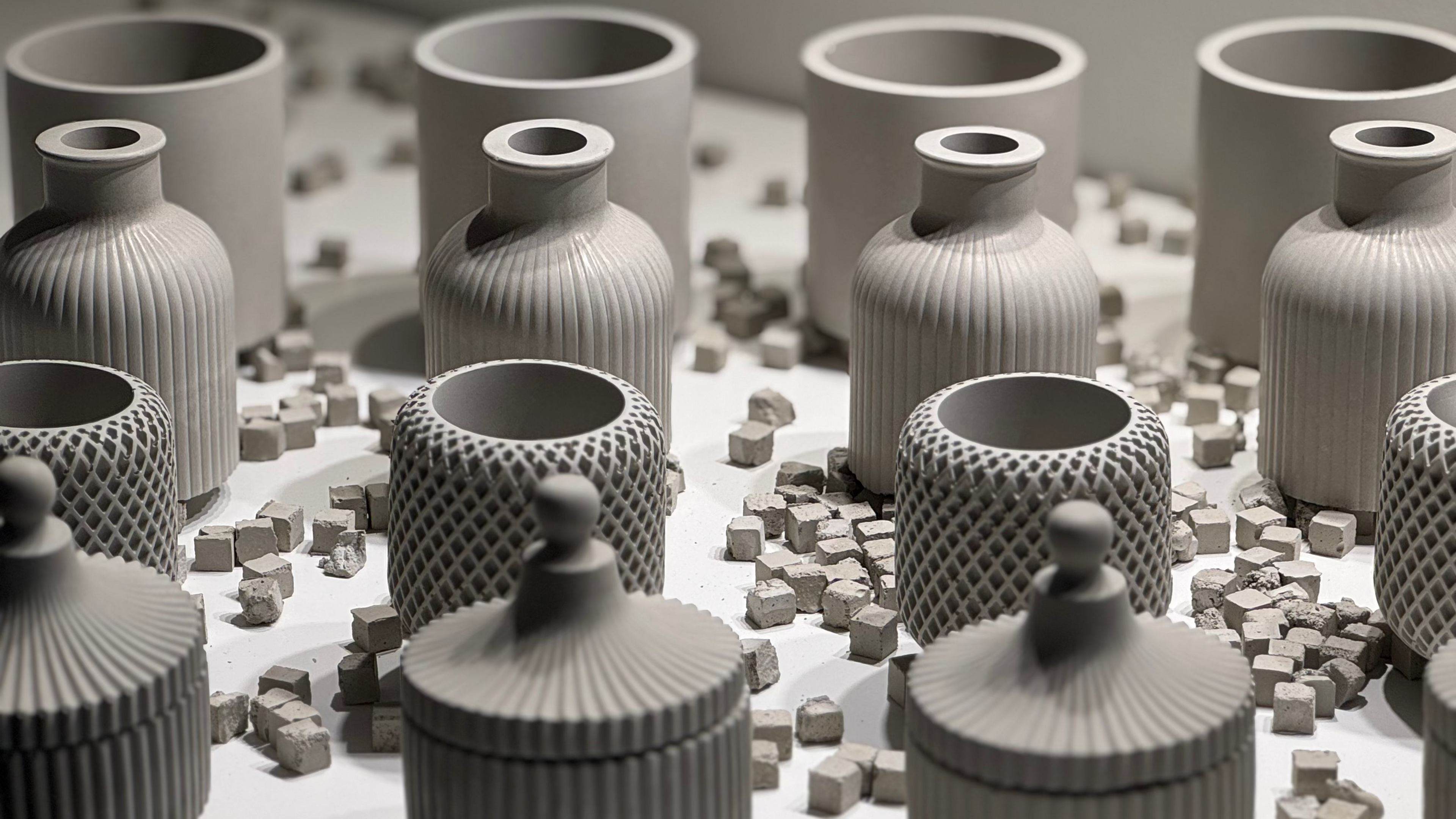 Collection of gray ceramic vases with textured surfaces on a light background
