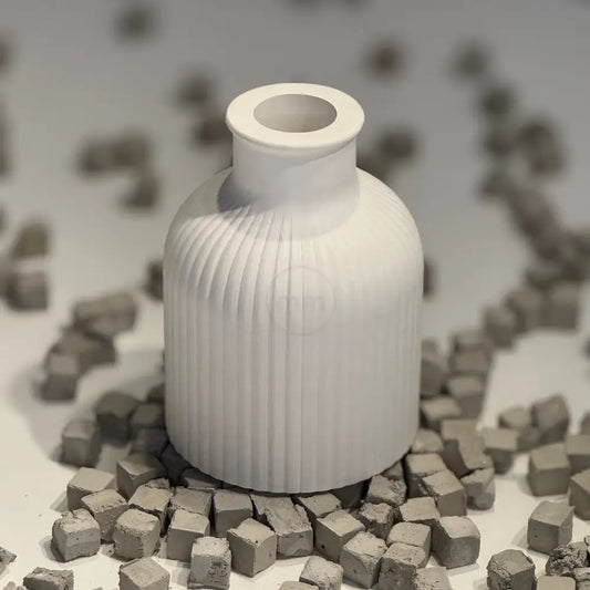 White ribbed vase surrounded by small gray cubes on a white background